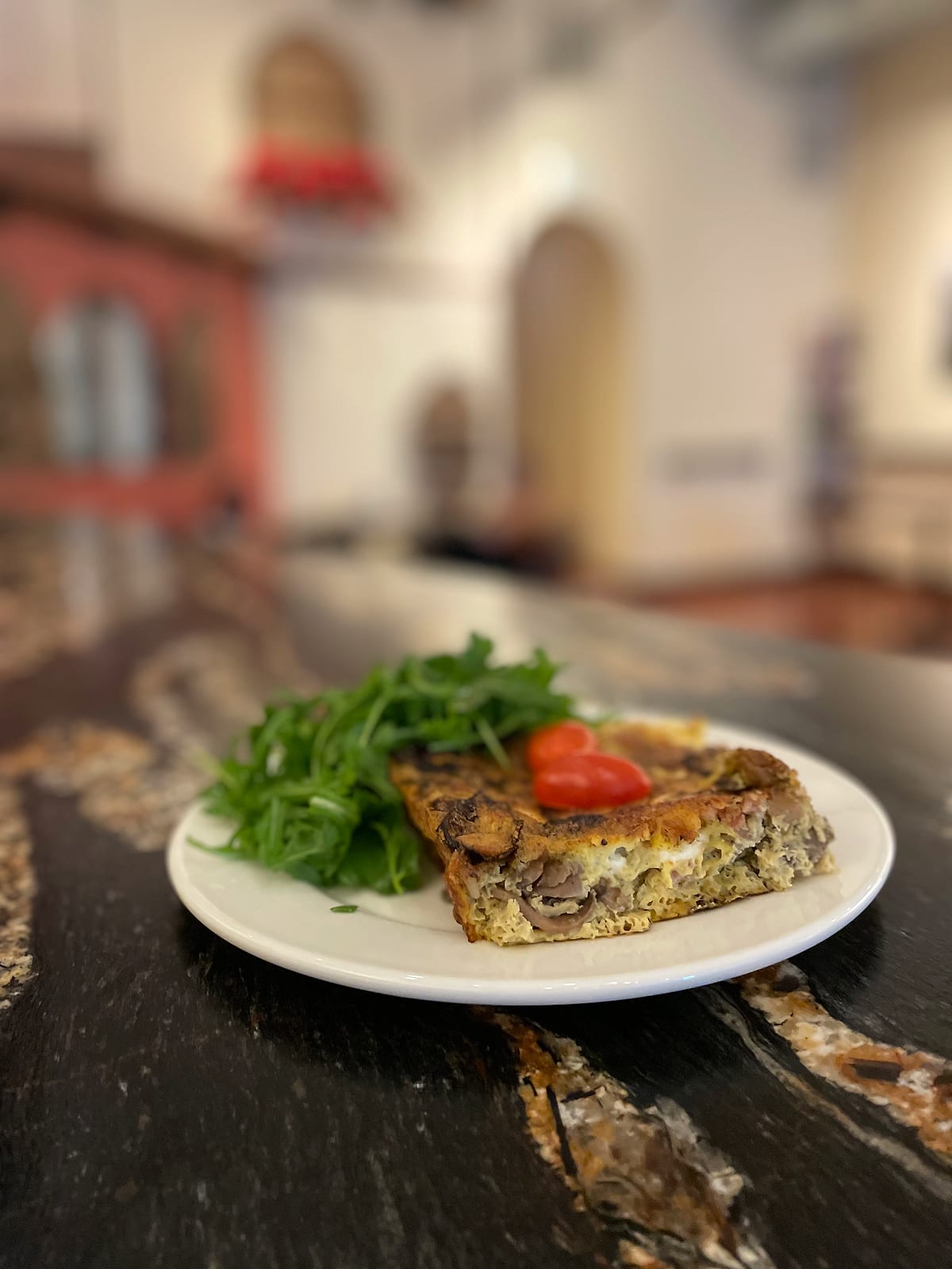 A slice of vegetable frittata with arugula salad