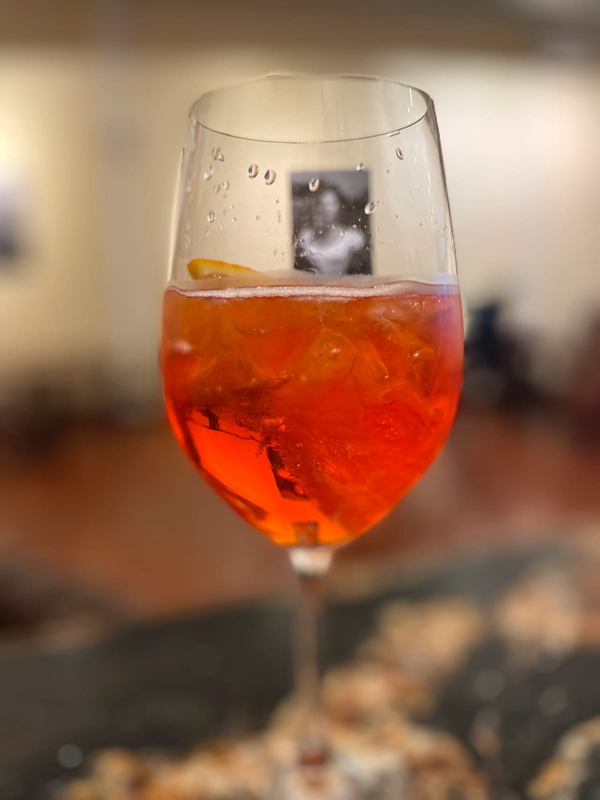 An orange spritz in a wine glass on the marble bar
